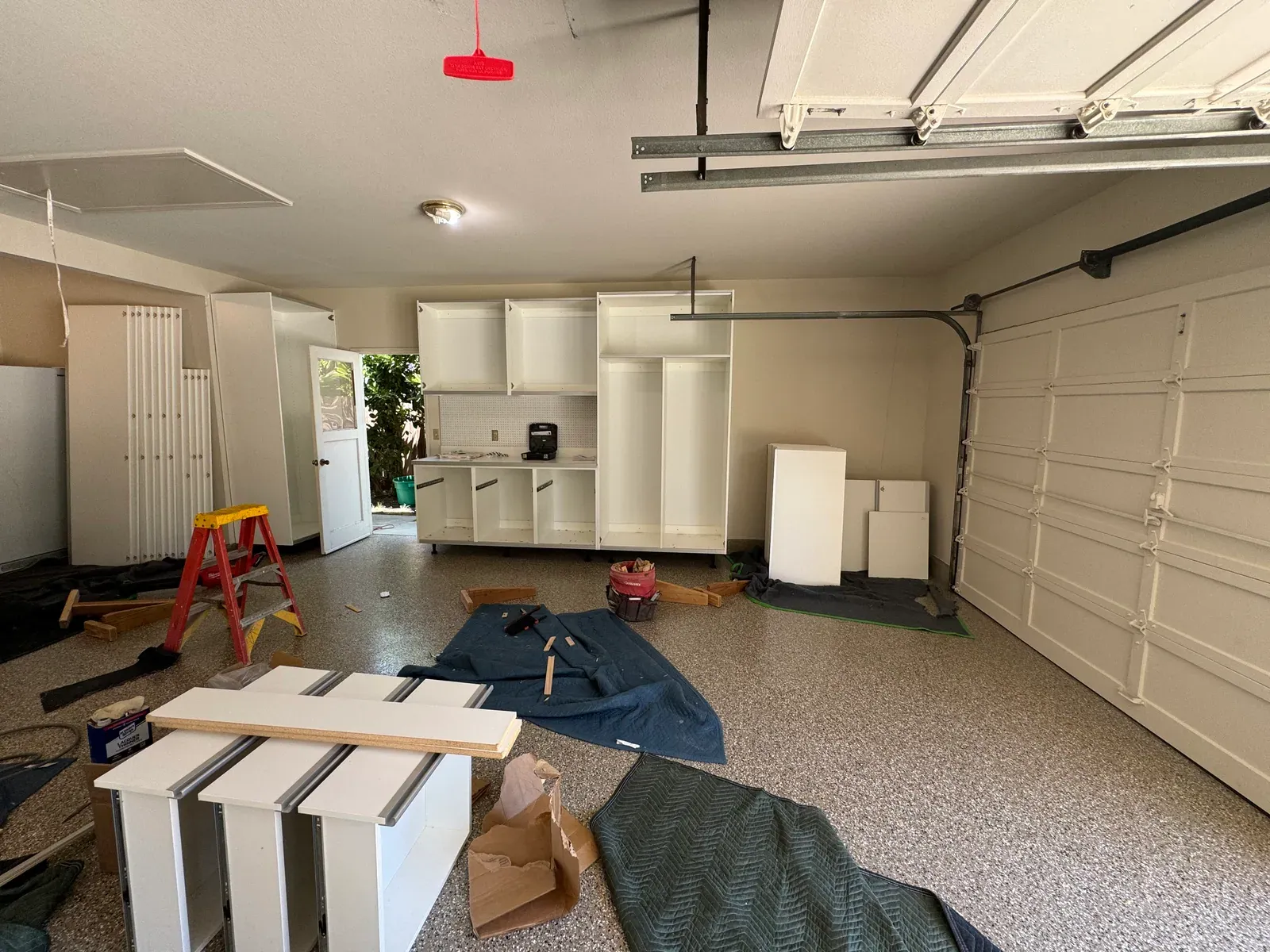 Upper cabinets, a counter and a tall locker going in along a garage wall during an install.