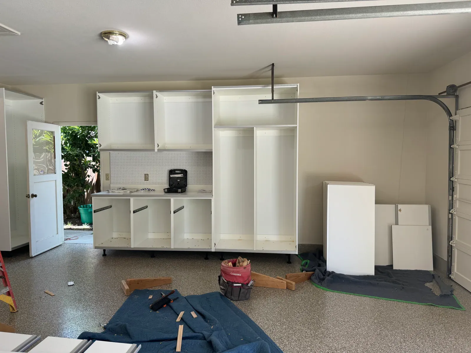 Upper cabinets over a pegboard backsplash with the drawer boxes still open, part-way through an install.