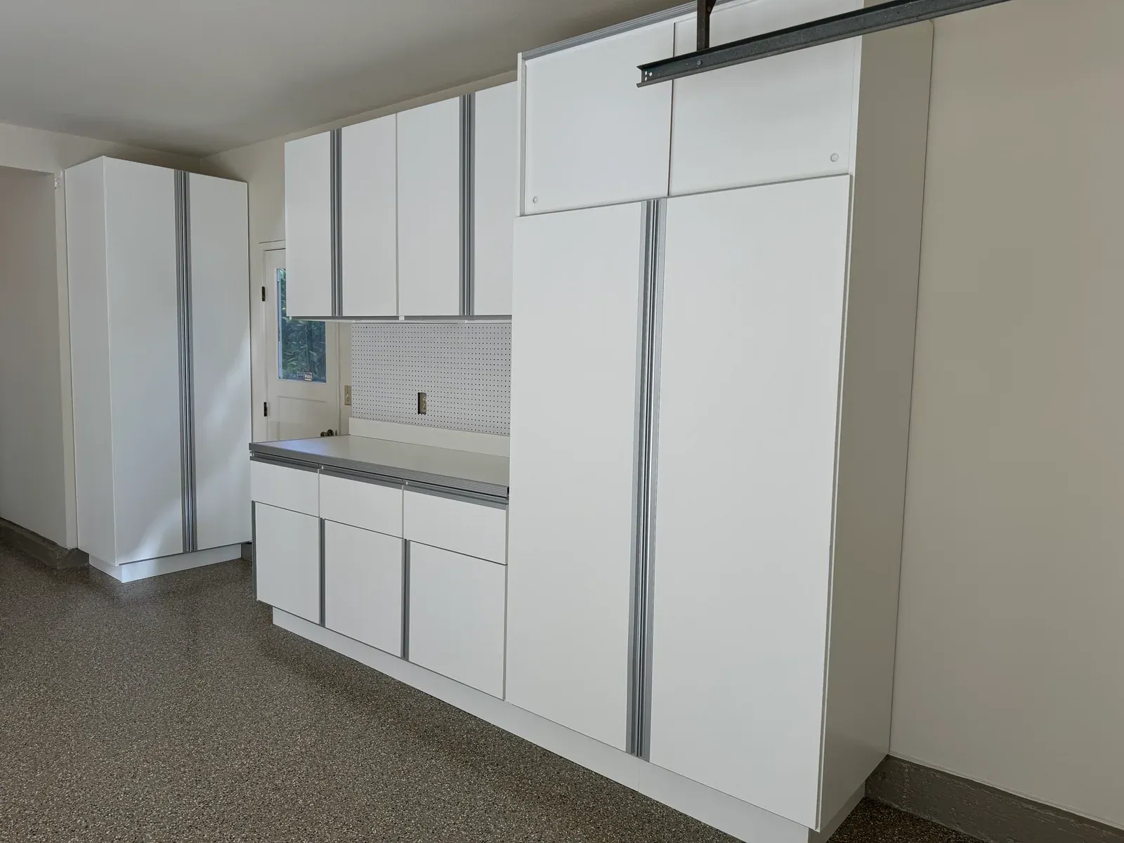 A finished corner: tall cabinets, upper cabinets over a counter with a perforated backsplash, and drawers below.