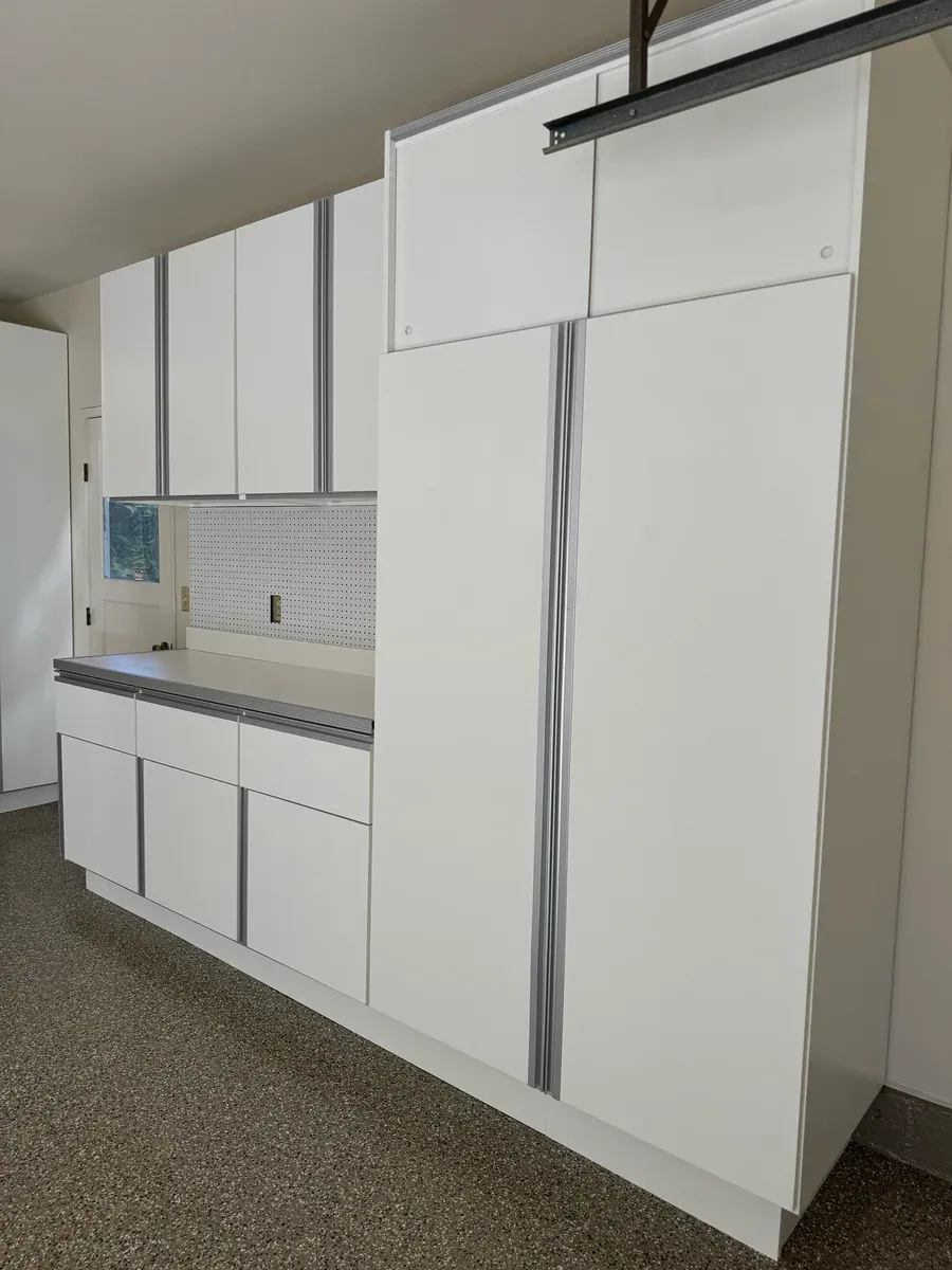 A finished run seen down the wall: counter with drawers below, upper cabinets and a tall cabinet at the end.