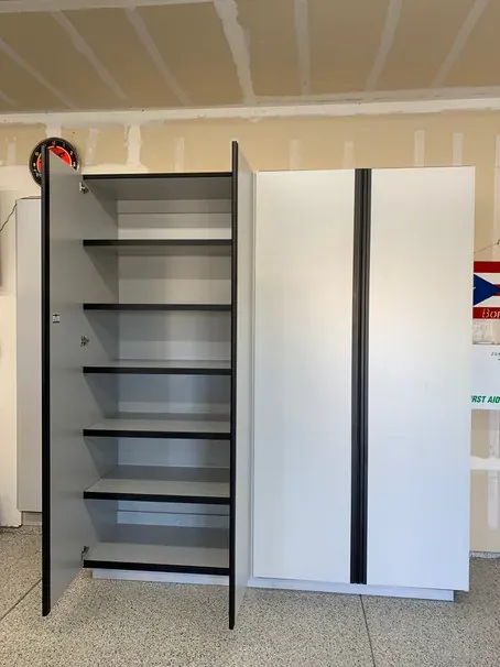 A tall garage cabinet standing open with six shelves inside, next to a closed two-door cabinet.