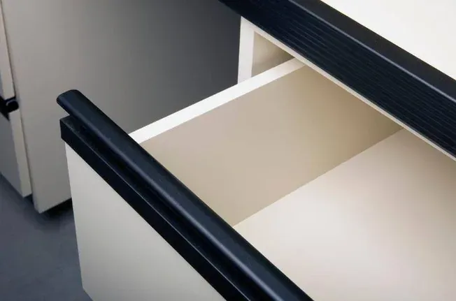 An open drawer with a dark aluminum finger pull handle running along its front edge.