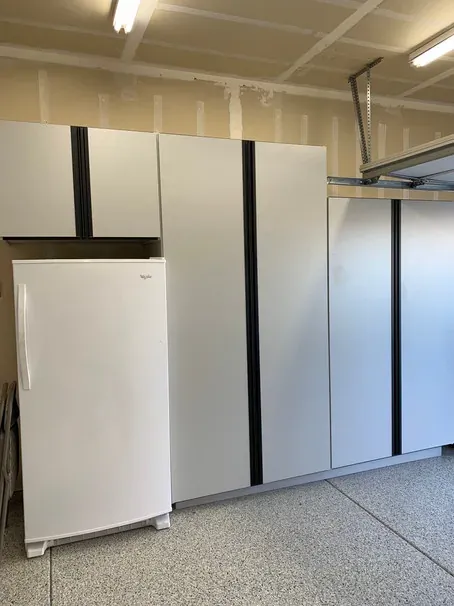 A white cabinet run built around a full-height freezer, with a tall cabinet on either side.