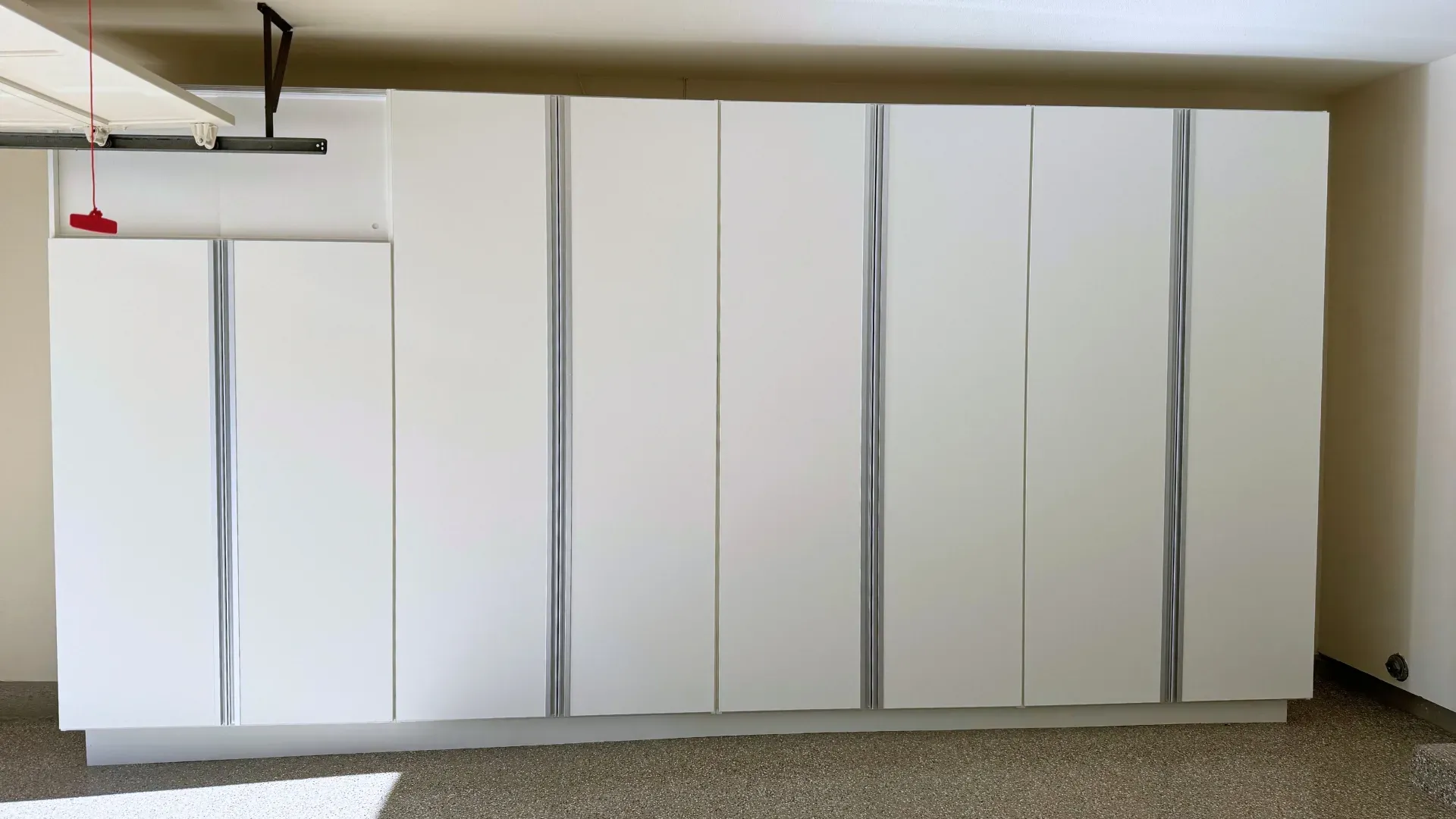 A run of full-height grey garage cabinets along a finished garage wall.